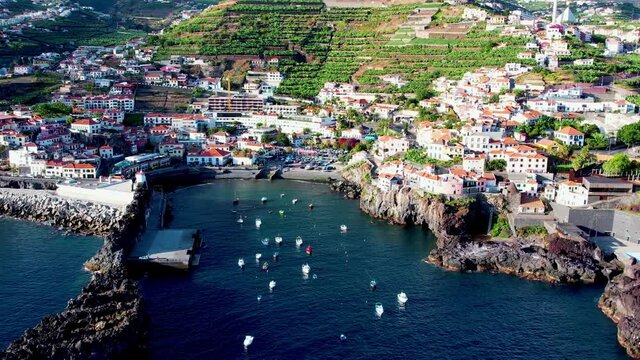 Aerial 4K footage of drone flight over Camara de Lobos fisherman village in Madeira Island with a bay with many small boats