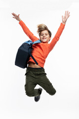 Joyful boy with a backpack is jumping. A guy in dark jeans and an orange sweater. Positivity,...