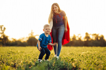 mom and son plant a tree in the park, mom and son in superhero costumes, Side view of a happy...