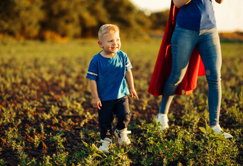 concept of super mom with baby, mom with super hero cloak runs after baby, outdoors