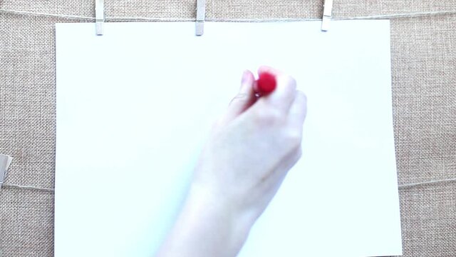 A woman's hand draws red heart on a white sheet of paper with red marker. The concept of love, relationships, Valentine's Day.