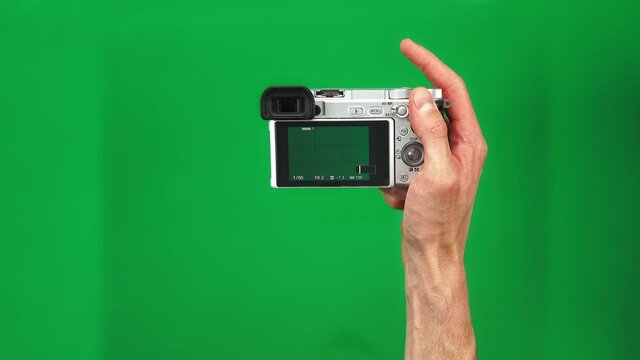Set of 4 gestures of male hands holding silver photo camera and pushing button on green screen background. The man is taking picture on slr tapping on it against alpha channel. Concept shooting images