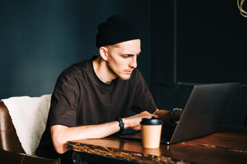 Young man mobile developer writes program code on a computer, programmer work in home office.