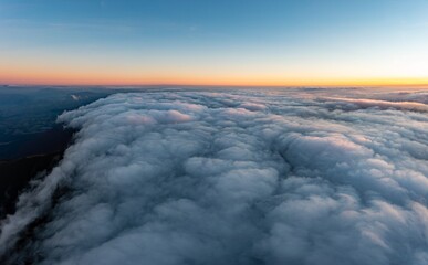 Thick layer of white clouds above mountains at sunrise