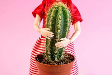 Woman doll hugs a cactus plant on light pink background. Harmful, painful and toxic relationship, partner problems, emotional abuse concept.
