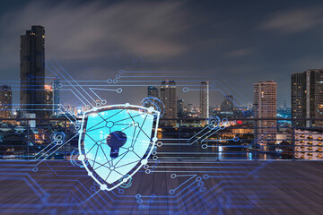 Rooftop with wooden terrace, Bangkok night skyline. Cyber security concept to protect clients confidential information. IT hologram padlock icons. City downtown. Double exposure.