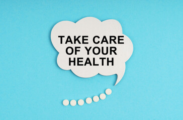 On a blue table are pills and a white plate with the inscription - Take care of your health