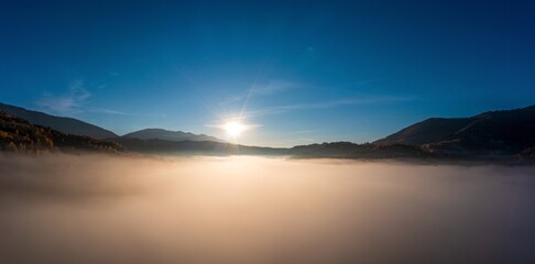 Fototapeta na wymiar Sunset light among clouds above mountainous canyon in mist