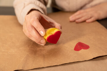 heart shaped potato stamp on craft paper. The process of decorating a gift for Valentine's Day. Getting ready for the celebration on February 14th.
