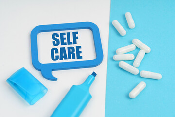 On the white and blue surface are a marker, tablets and a plate inside which the inscription - Self Care