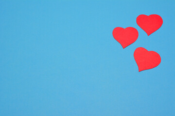 Fototapeta na wymiar red paper hearts on blue background, place for text