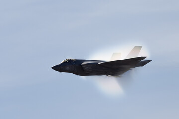 Fototapeta na wymiar Very unusual close view of a F-35C Lightning II at very high speed, with condensation cone (“singularity”) around the plane