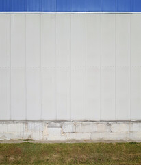 Fototapeta na wymiar fragment of the facade of an industrial building, metal facade panels and concrete foundation of the building, backyard, source or template
