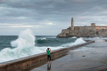 Big waves on Malecon streets during sunrise with storm clouds in background. Havana, Cuba