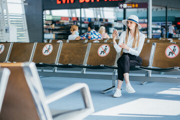 Obraz premium Travel tourist woman standing with luggage check flight number on smartphone airport. Young business girl with her suitcase waiting at boarding gate before departure. Travel lifestyle concept.