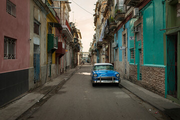 Naklejka na ściany i meble Amazing old american car on streets of Havana with colourful buildings in background. Havana, Cuba.