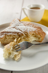 A curd cheese turnover, a Danish pastry filled with curd cheese, served on a plate. On a wooden table.