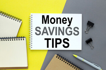 MONEY SAVINGS TIPS Concept for management and business.Open laptop and other office supplies Yellow and gray