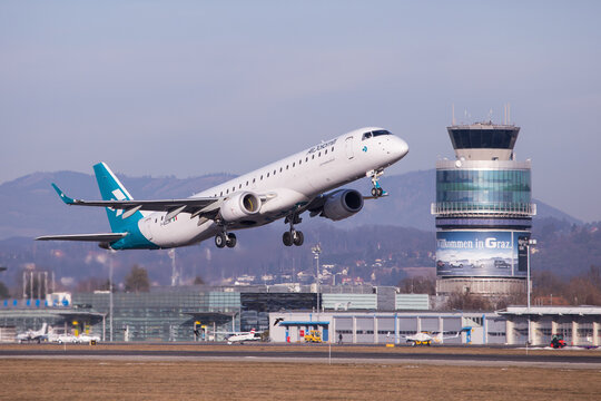 Air Dolomiti airplane departing aerodrome Graz for a flight to Munich with airport buildings and air traffic control tower in the background 