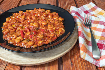 Shrimps with tomato red sauce on wooden table. Side view.