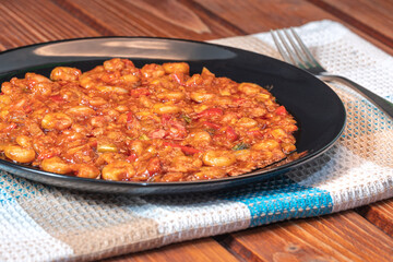 Shrimps with tomato red sauce on wooden table. Side view.