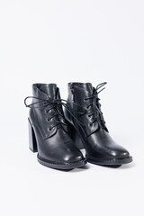 Women's boots with black genuine leather on heels isolated on a white background. photo from the side, diagonally and foreshortened from behind. Women's shoe collection 2022