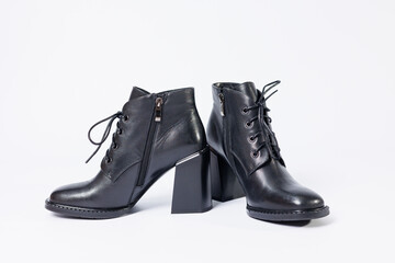 Women's boots with black genuine leather on heels isolated on a white background. photo from the side, diagonally and foreshortened from behind. Women's shoe collection 2022
