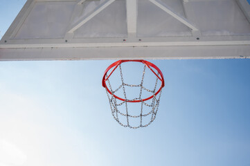 Bottom view of the background of a basketball hoop against the blue sky. 