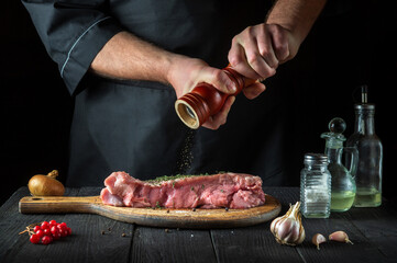 The chef prepares raw veal meat. Before baking, the chef adds pepper to the beef. National dish is being prepared in the restaurant kitchen