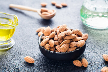 Fresh peeled almonds in a bowl close-up of almond oil behind on the table. A source of vitamins and oils. Natural cosmetics