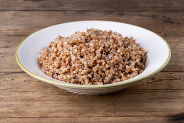 buckwheat in a white plate on a wooden background