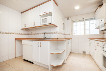 Kitchen with white cabinets and wood-colored countertops with white appliances and tile trim