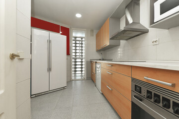 Kitchen with cherry wood furniture, white countertop, gray appliances with a large two-door refrigerator on one side