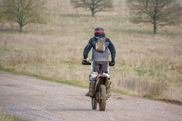 a motor cyclist (biker) riding his off-road motorbike along a stone track 