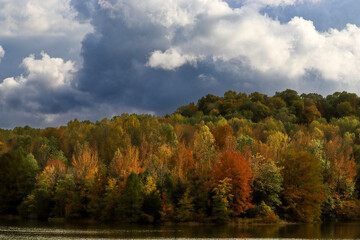 Obraz premium Stunning, fall foliage framed by a beautiful lake below and storm clouds above.