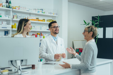 Two pharmacist giving prescription medications to senior female customer in a pharmacy