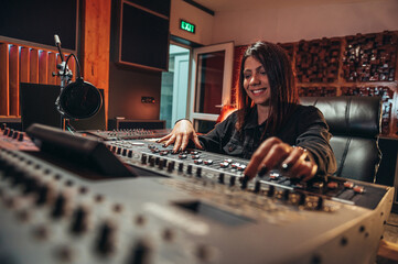 Young woman music producer working on a mixing soundboard while in her studio