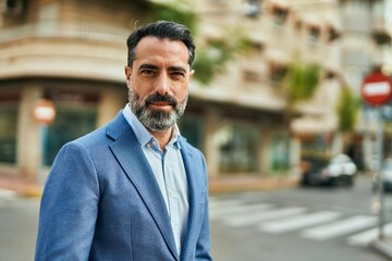 Middle age businessman with relaxed expression standing at the city.