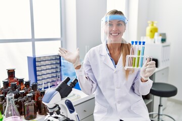 Beautiful woman working at scientist laboratory celebrating achievement with happy smile and winner expression with raised hand