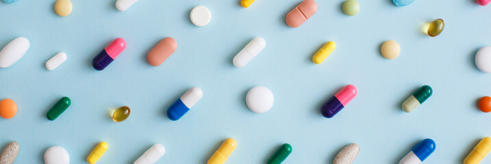 Banner made Creative layout of colorful pills and capsules on blue background. Minimal medical...