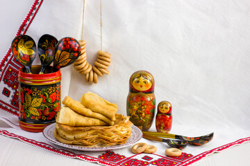 Background with pancakes, wooden utensils with Khokhloma painting, matryoshka, rushnik, sushki for...