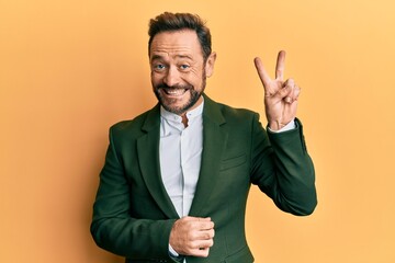 Middle age man wearing business suit smiling with happy face winking at the camera doing victory...