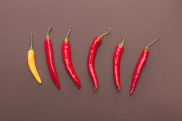 Fotobehang red and yellow chili peppers on brown background © aerogondo