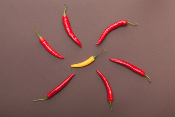 red and yellow chili peppers isolated on brown background