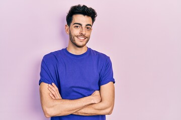 Young hispanic man wearing casual t shirt happy face smiling with crossed arms looking at the camera. positive person.