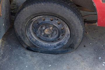 Fototapeta na wymiar Destroyed blown out tire with exploded, shredded and damaged tire on a modern automobile. damaged truck rubber after tire explosion at high speed. Damaged flat tires: old car.