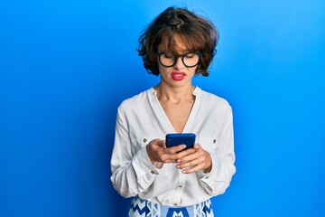 Young brunette woman using smartphone clueless and confused expression. doubt concept.