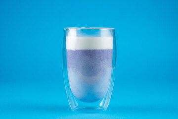 Purple goji matcha on blue background. Matcha cocktail in double glass cup.