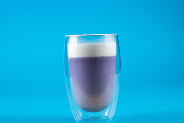 Purple goji matcha on blue background. Matcha cocktail in double glass cup.