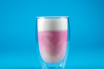 Pitahaya pink matcha on blue background. Matcha from dragon fruit cocktail in double glass cup.